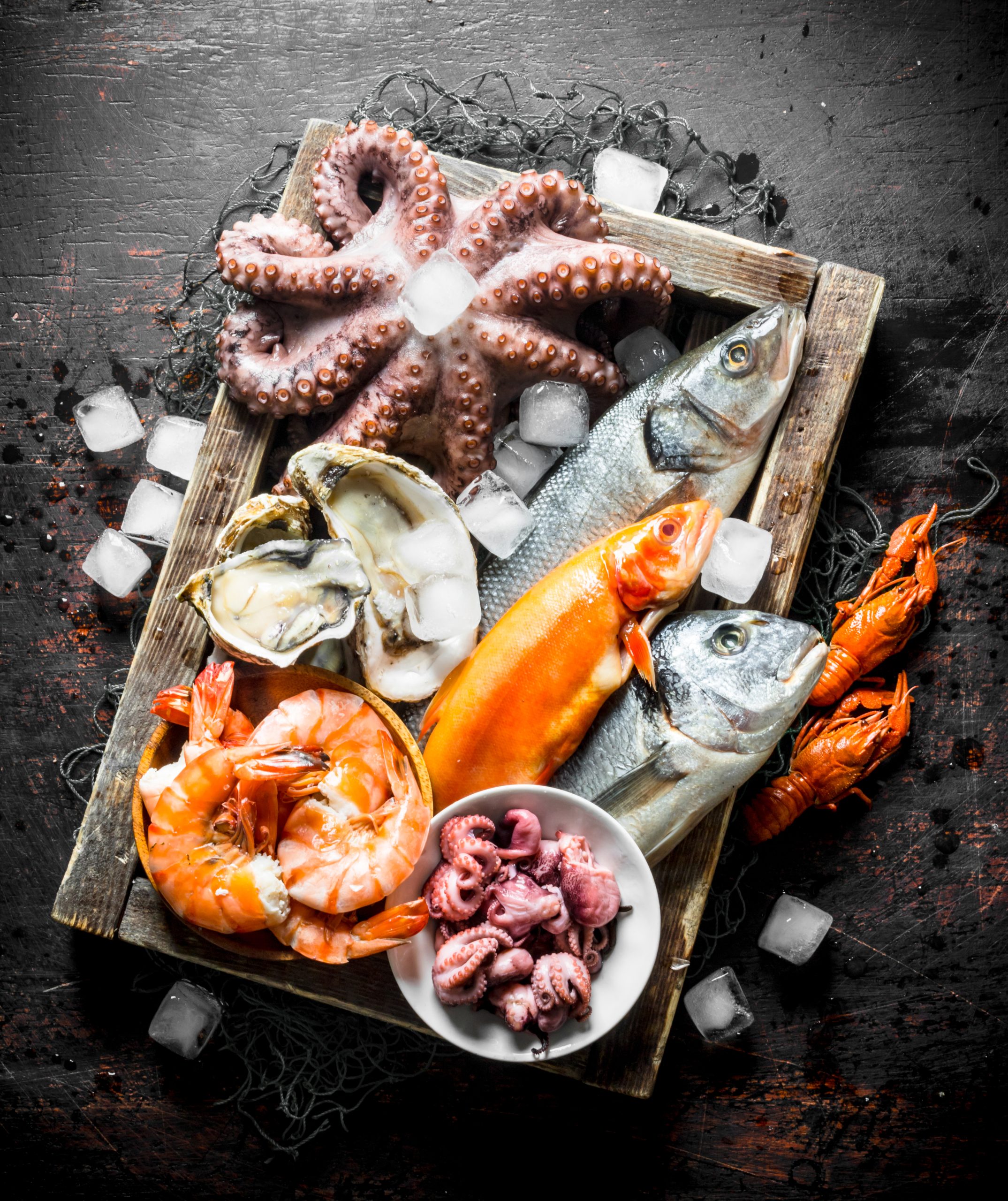 Delicious fresh seafood on a wooden tray with ice. On dark rustic background